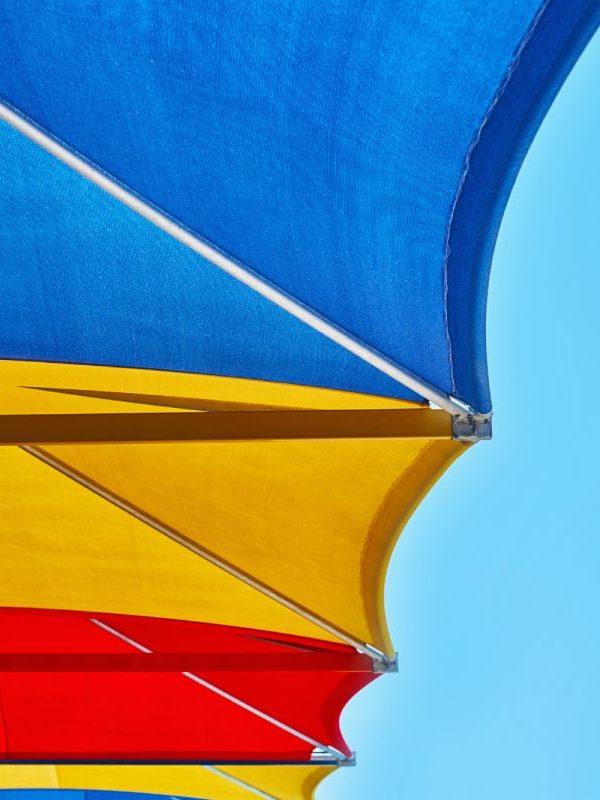 Colored beach shade sail against blue sky in summer day