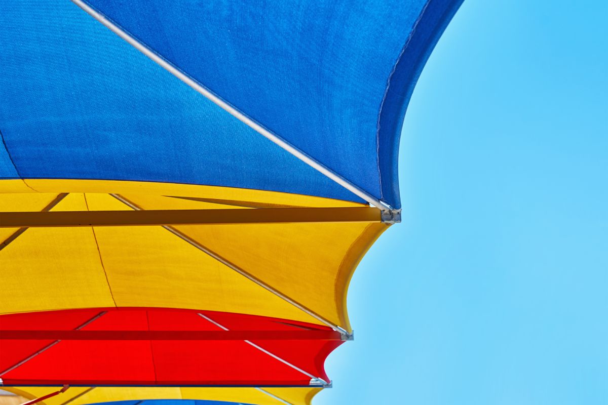 Colored beach shade sail against blue sky in summer day