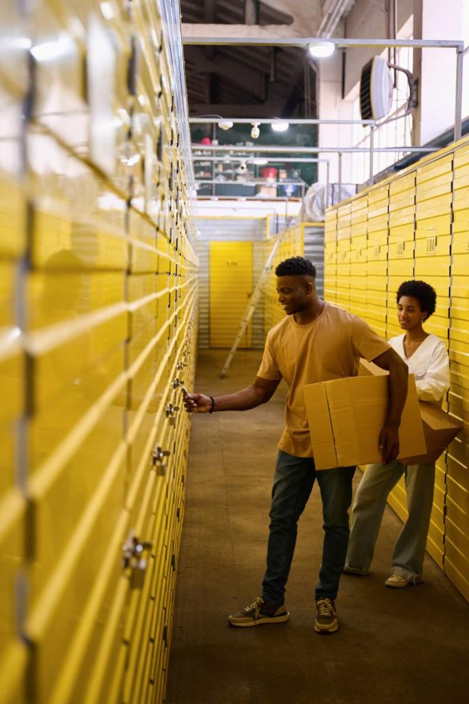 African American man opens a storage unit, next to his girlfriend with cardboard boxes