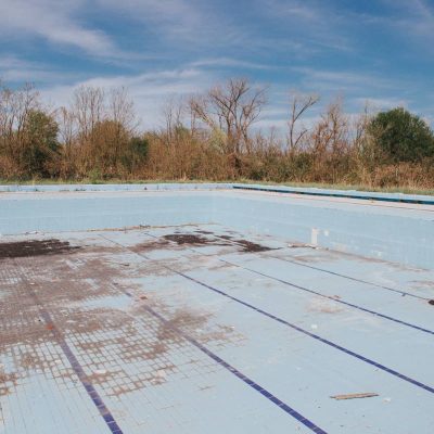 An old empty dry outdoor swimming pool in a dry park