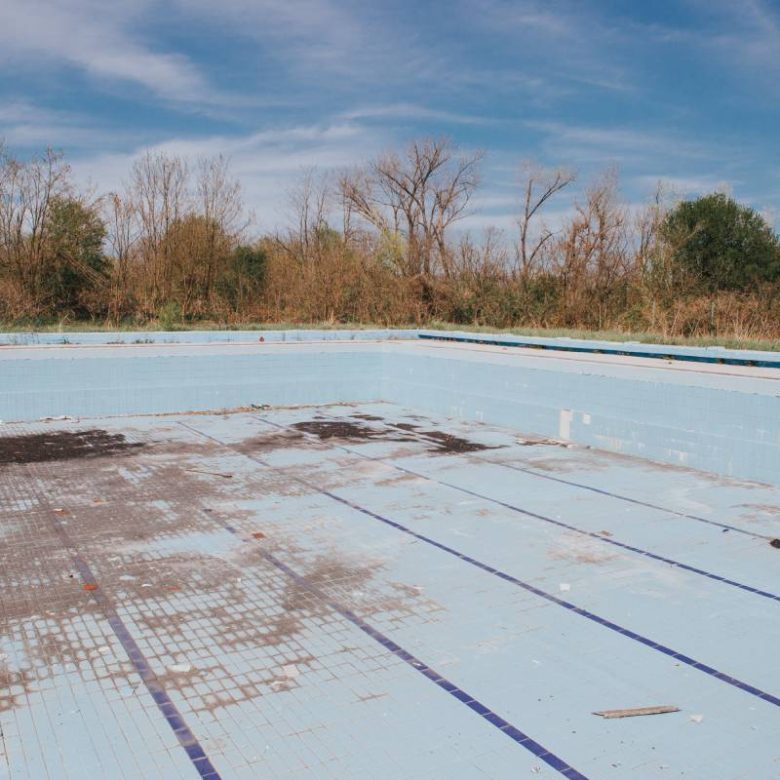 An old empty dry outdoor swimming pool in a dry park